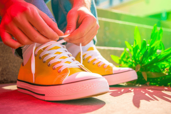 Person safely fixing shoelaces using heat with gloves and a lighter on a clean surface