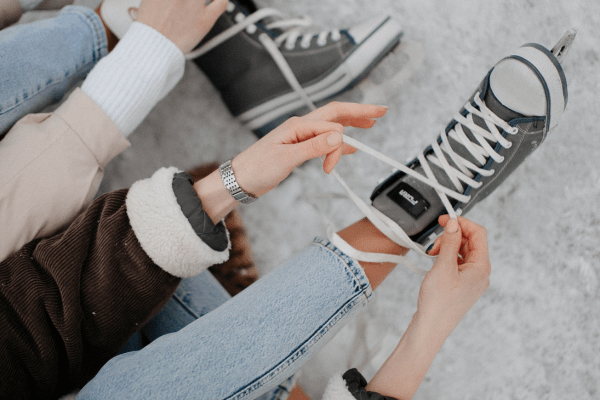 Person demonstrating how to tie shoelaces in different styles on ice skates.