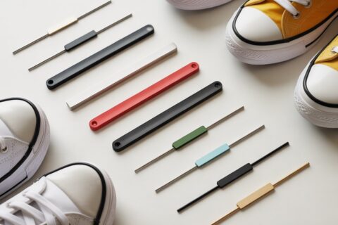Flat lay comparison of metal, plastic, and magnetic shoelace bar styles displayed next to sneakers on a clean background.