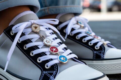 Close-up of stylish sneakers with metal shoelace charms attached to white flat laces, trendy 2026 sneaker accessory design